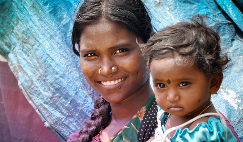 Das Bild zeigt eine lächelnde Frau, das ein Kleinkind am Arm hält.