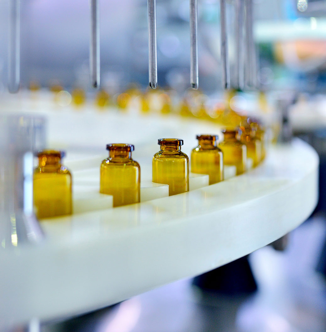 Das Bild zeigt eine Arzneimittelproduktionsstraße mit gelben Grasfläschchen